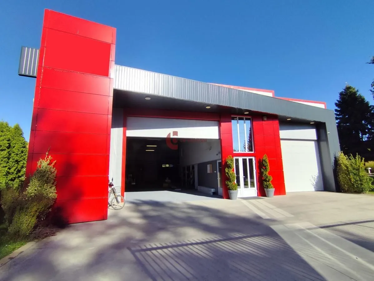 Exterior view of a modern commercial building with red details and entrance doors.
