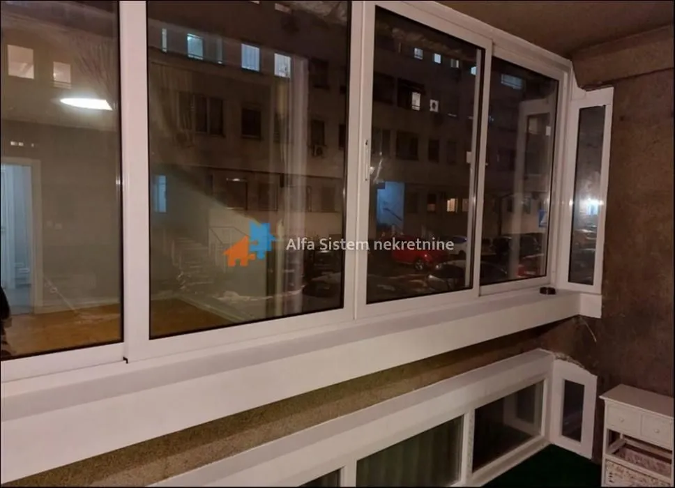 Enclosed balcony with large windows and a view of surrounding buildings.