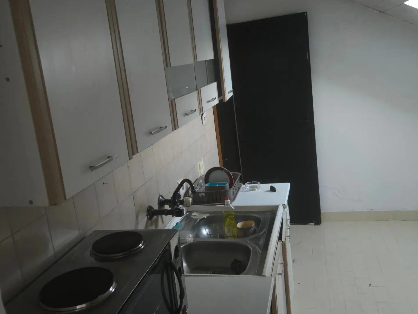Manja kuhinja sa sudoperom, elementima i električnim šporetom.