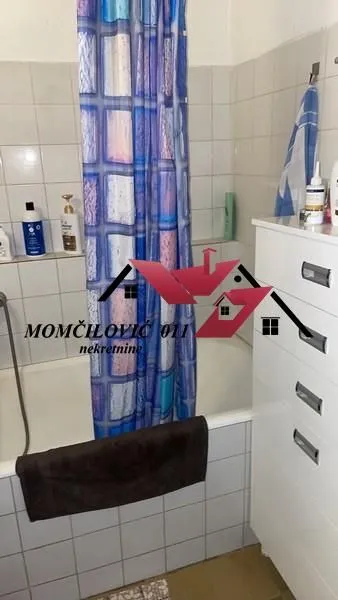 Manje kupatilo sa kadom, plavom zavesom za tuširanje i belom komodom.