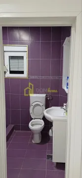 Small bathroom with purple tiles, toilet, and vanity with sink. - image 8