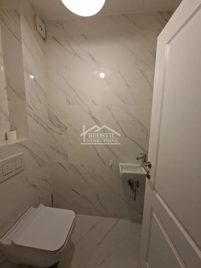 Smaller bathroom tiled with marble-patterned ceramic tiles.