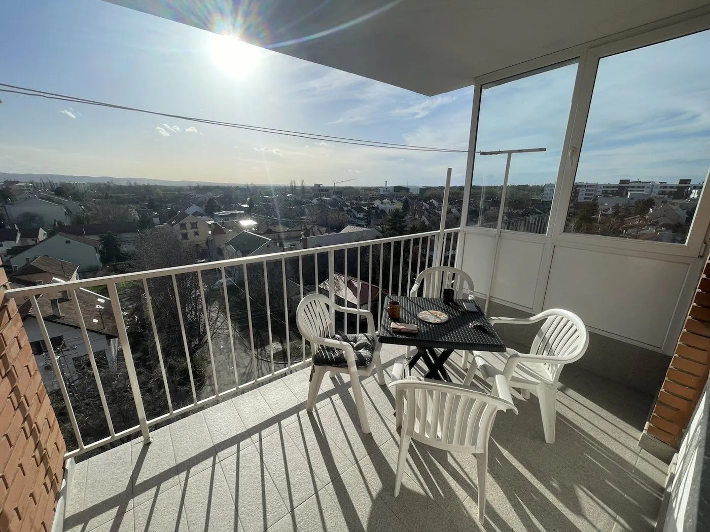 Furnished balcony with a table, chairs, and city view.