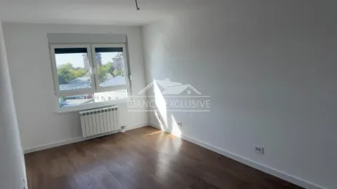 Prazna soba sa belim zidovima, drvenim podom i prozorom koji gleda na okolinu. - image 4
