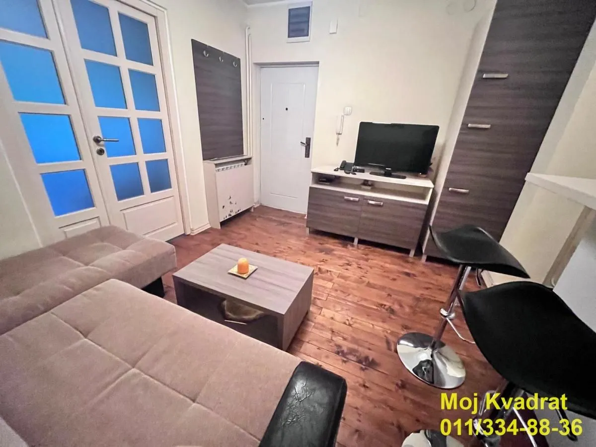 Dnevna soba sa garniturom, stočićem i televizorom.