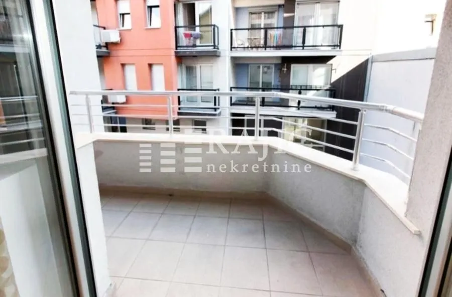 Small tiled balcony with metal railing and a view of the building.