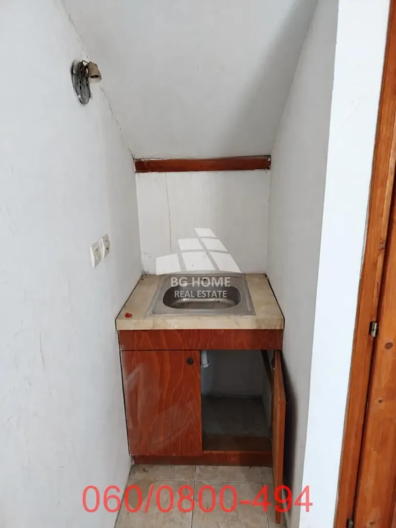 Small kitchen nook with a sink and wooden cabinets in the attic.