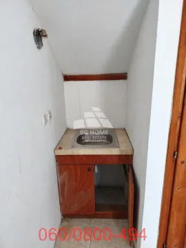 Small kitchen nook with a sink and wooden cabinets in the attic. - image 13