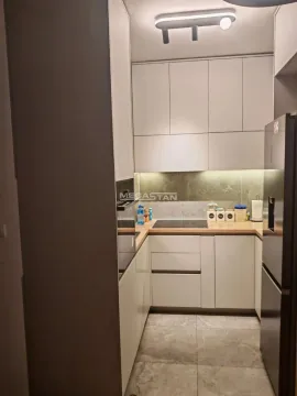 Pogled na manju moderno opremljenu kuhinju sa belim elementima i ugradnim aparatima. - image 6