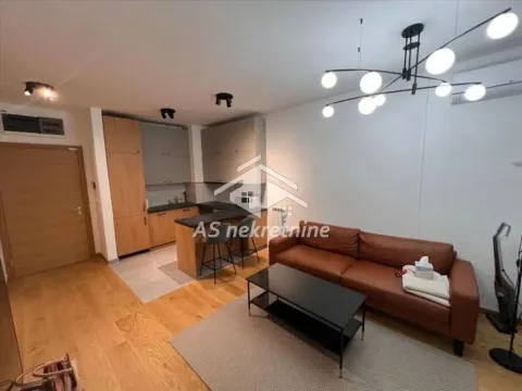 Living room with a sofa and kitchen in the background. - image 3