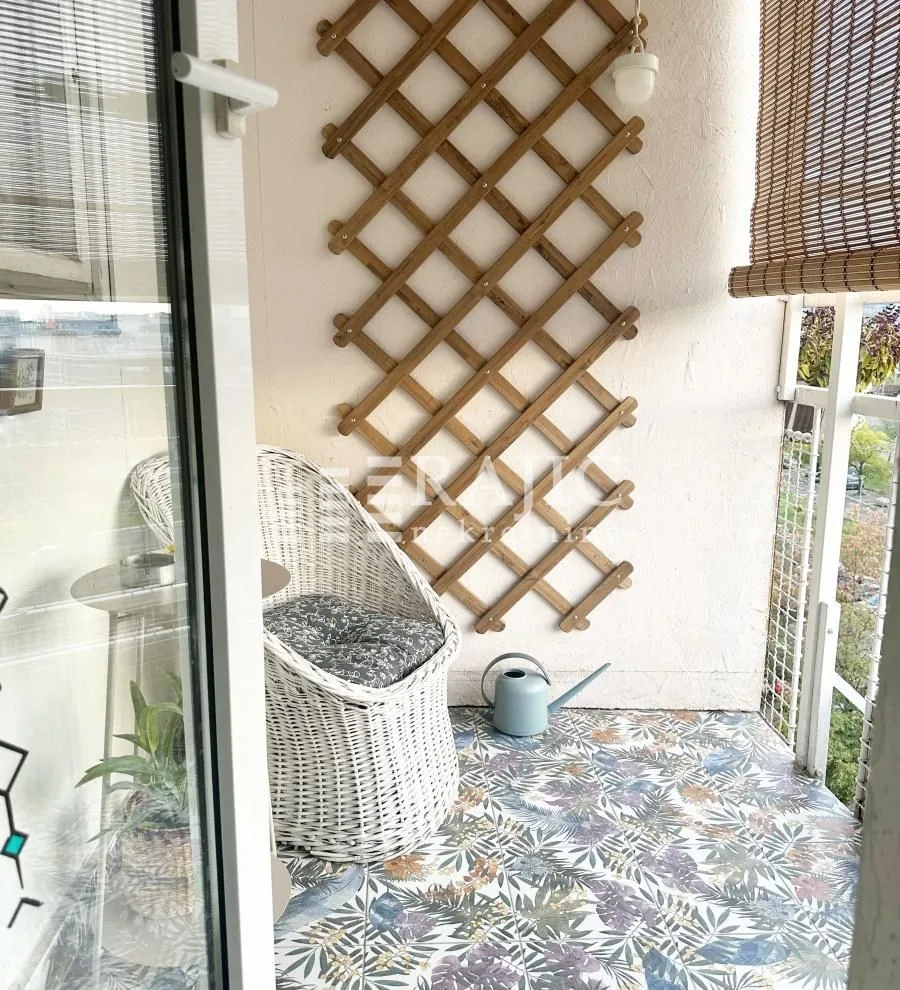 Small furnished balcony with a wicker chair and a wooden trellis on the wall.