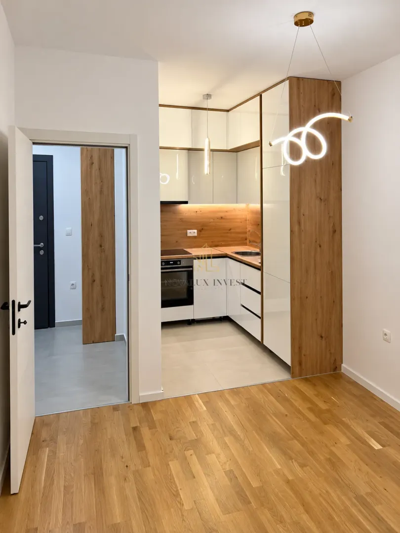 Modern fitted kitchen with white cabinetry and wood-tone accents.