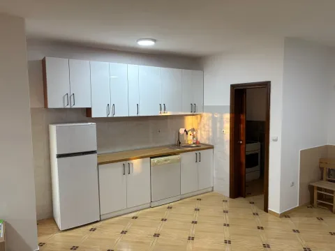 Small white kitchen with a wooden countertop and a refrigerator. - image 3