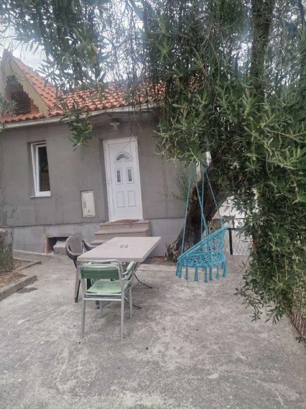 Yard of the house with a table, chairs, and a hanging swing.