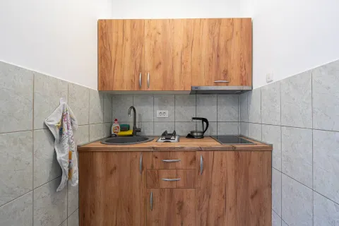 Manja kuhinja sa drvenim elementima, sudoperom i pločom za kuvanje. - image 4