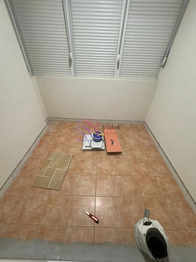Nenvistuirana terasa sa keramičkim pločicama i roletnama na prozorima.