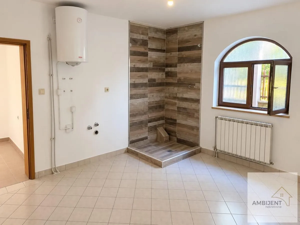 Kupatilo sa tuš kabinom obloženom pločicama u imitaciji drveta.