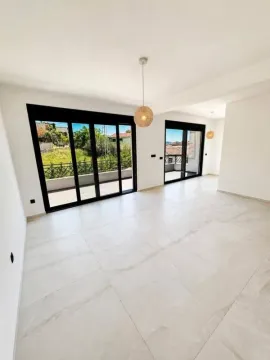 Spacious living room with large glass surfaces and exterior view. - image 12