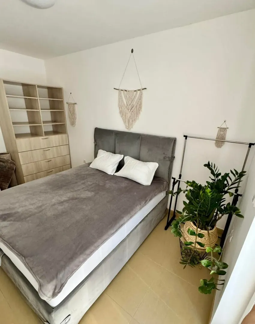 Furnished bedroom with a double bed, wardrobe, and decorative plants.