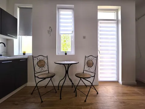 A small dining table with two chairs by the window in the kitchen. - image 10