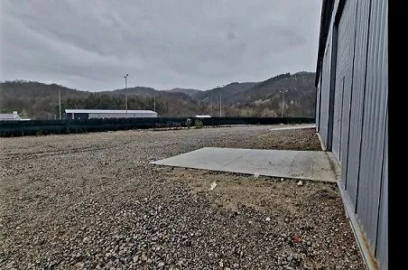 View of the yard and exterior of an industrial building with a gravel surface.