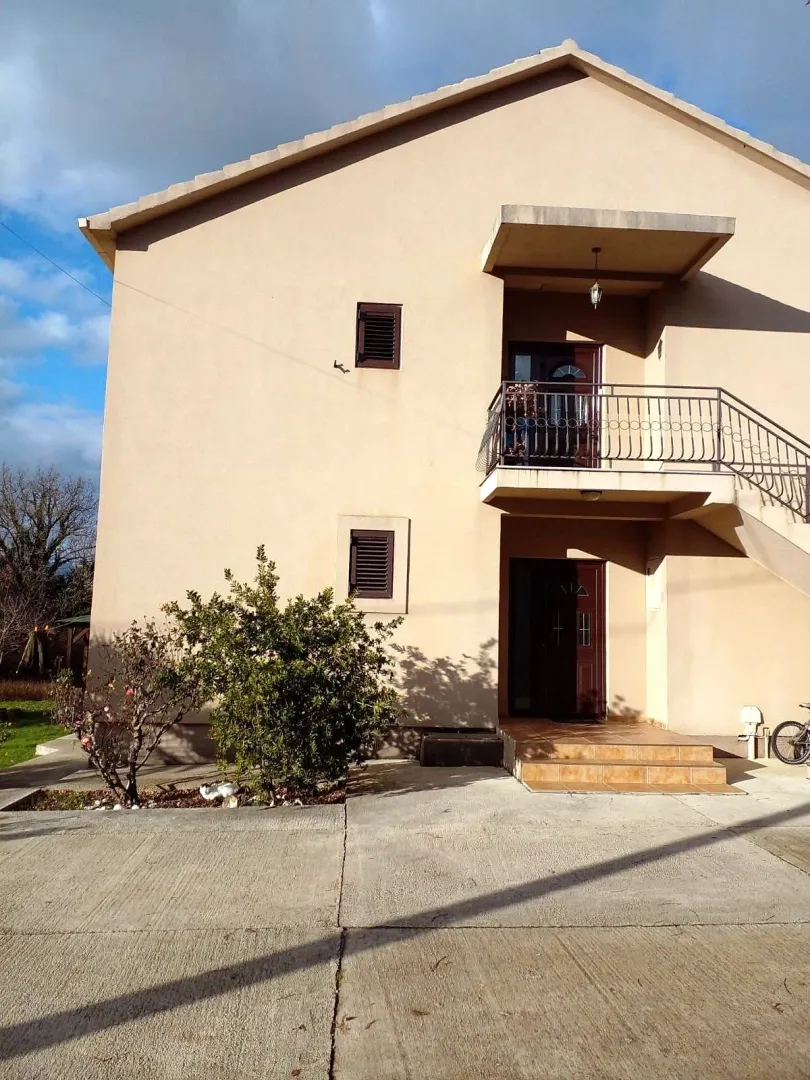 View of the exterior of the house with a balcony and yard.