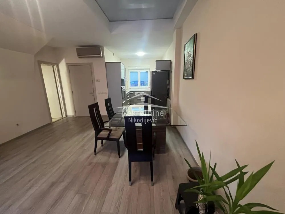 Dining area with a table and chairs, with a view of the kitchen in the background.