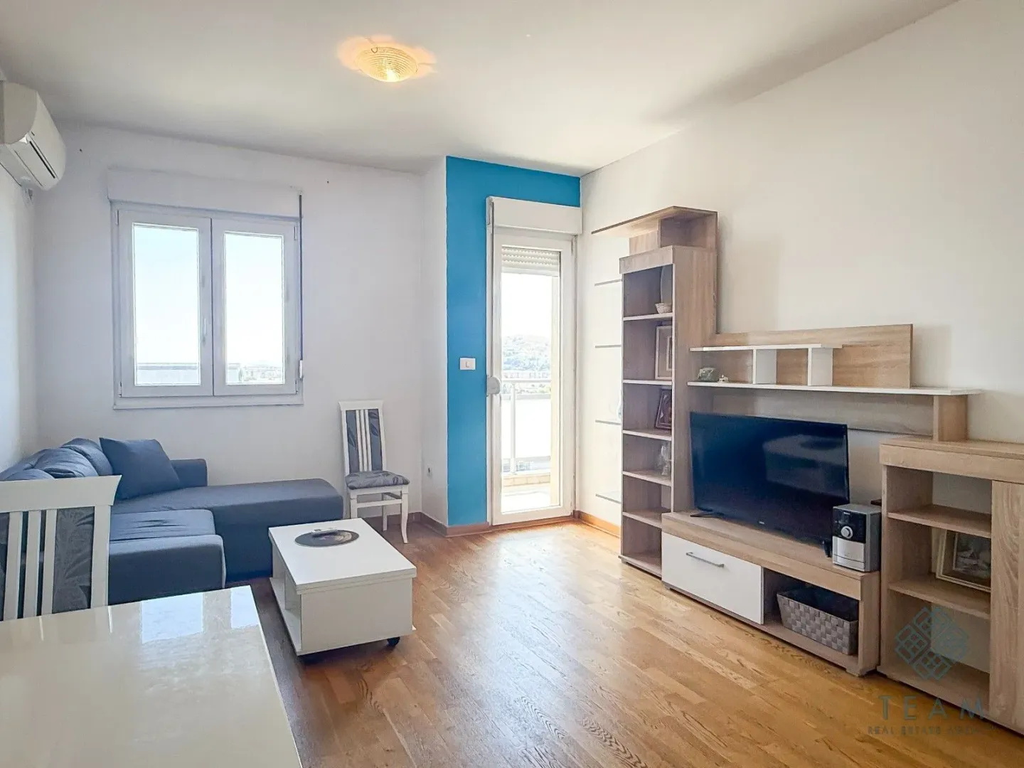 Living room with sofa, TV unit and balcony access.