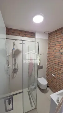 Bathroom with a shower cabin, toilet, and brick detail walls. - image 17