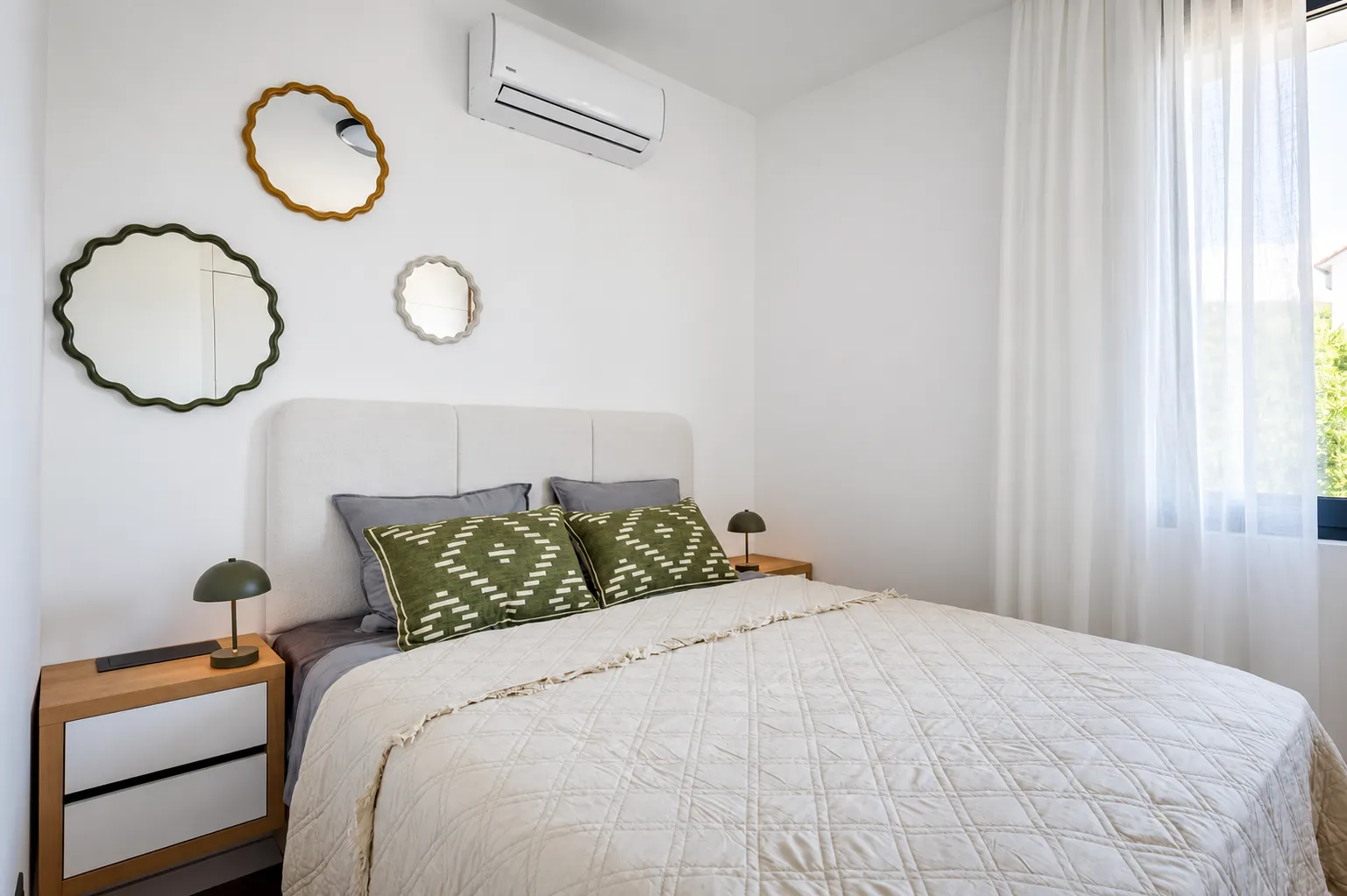 Bright bedroom with a double bed, bedside tables, and decorative wall mirrors.
