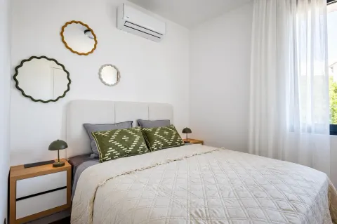 Bright bedroom with a double bed, bedside tables, and decorative wall mirrors. - image 16