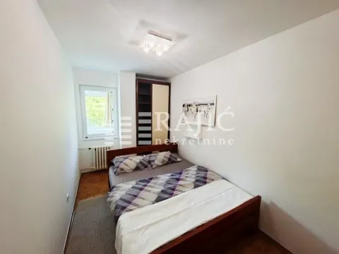 Manja spavaća soba sa bračnim krevetom, ormanom i prozorom. - image 7