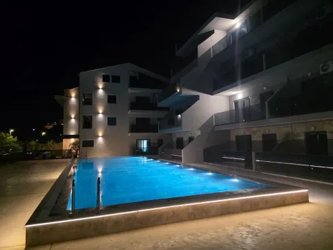 Noćni pogled na spoljašnjost zgrade sa osvetljenim bazenom. - image 16
