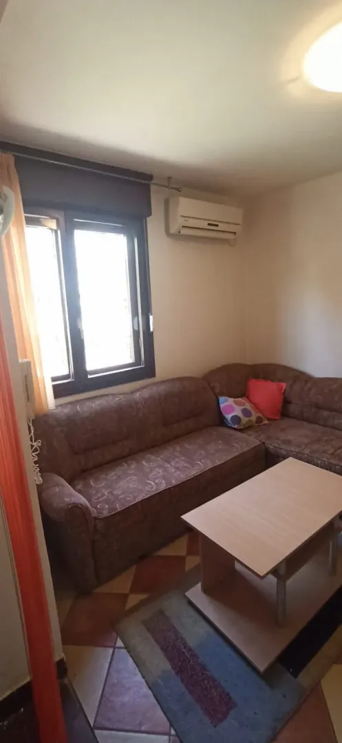 Dnevna soba sa ugaonom garniturom, stočićem i klima uređajem.