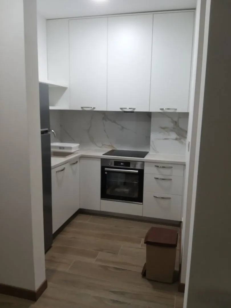 Moderna bijela kuhinja sa ugrađenom rernom i pločom za kuvanje.