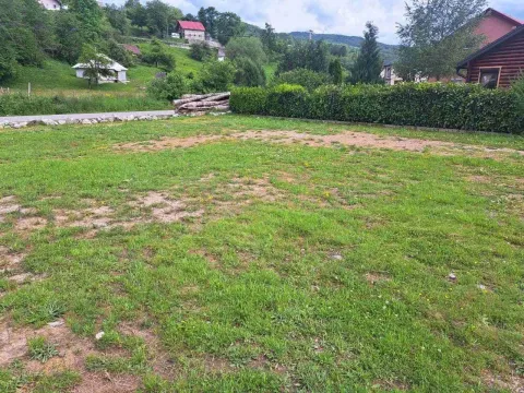 Prostrani travnati plac okružen prirodnim pejzažom i kućama. - image 4