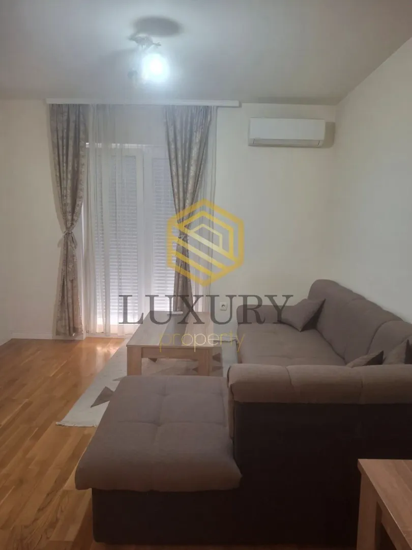 Living room with a sectional sofa, coffee table, and balcony doors.