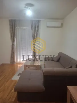 Living room with a sectional sofa, coffee table, and balcony doors. - image 2