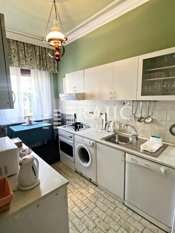Small kitchen with white cabinets, sink, and built-in appliances.