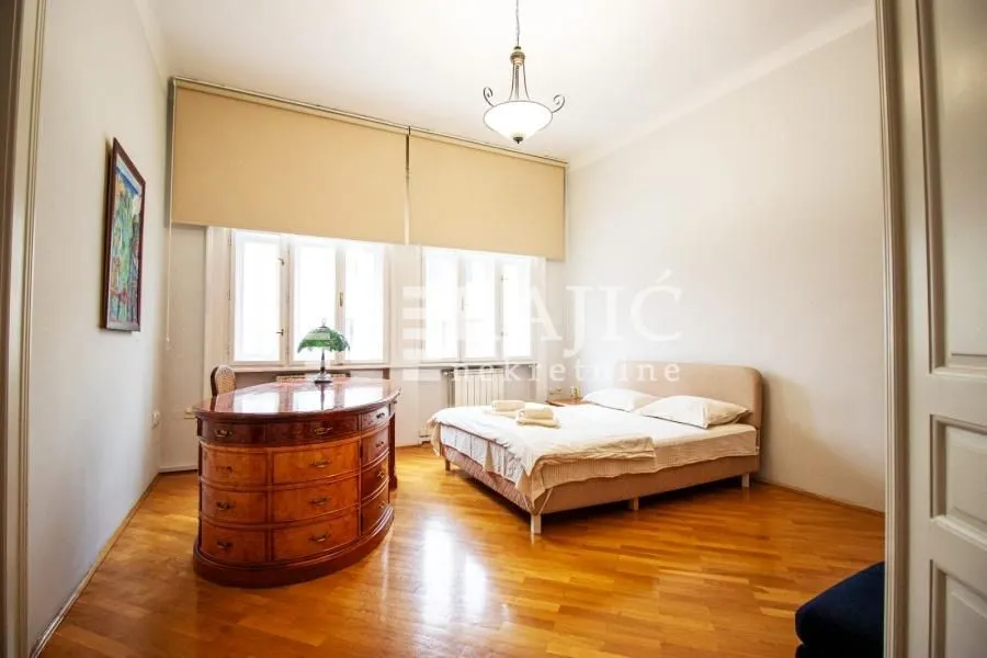 Spacious bedroom with a double bed, wooden furniture, and hardwood floors.