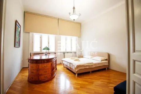 Spacious bedroom with a double bed, wooden furniture, and hardwood floors. - image 7