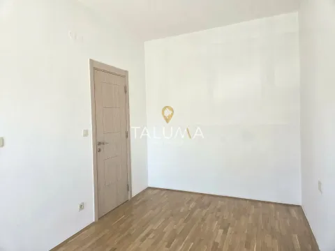 An empty room with white walls, wooden parquet flooring, and a closed door. - image 3
