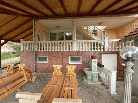 Natkrivena terasa ispred kuće sa drvenim klupama i stolovima. - image 9