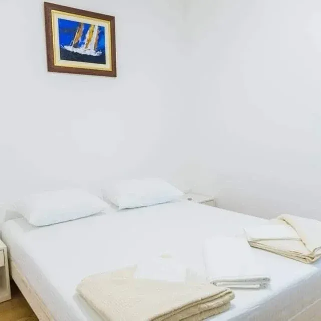 Bright bedroom with a double bed and a painting on the wall.