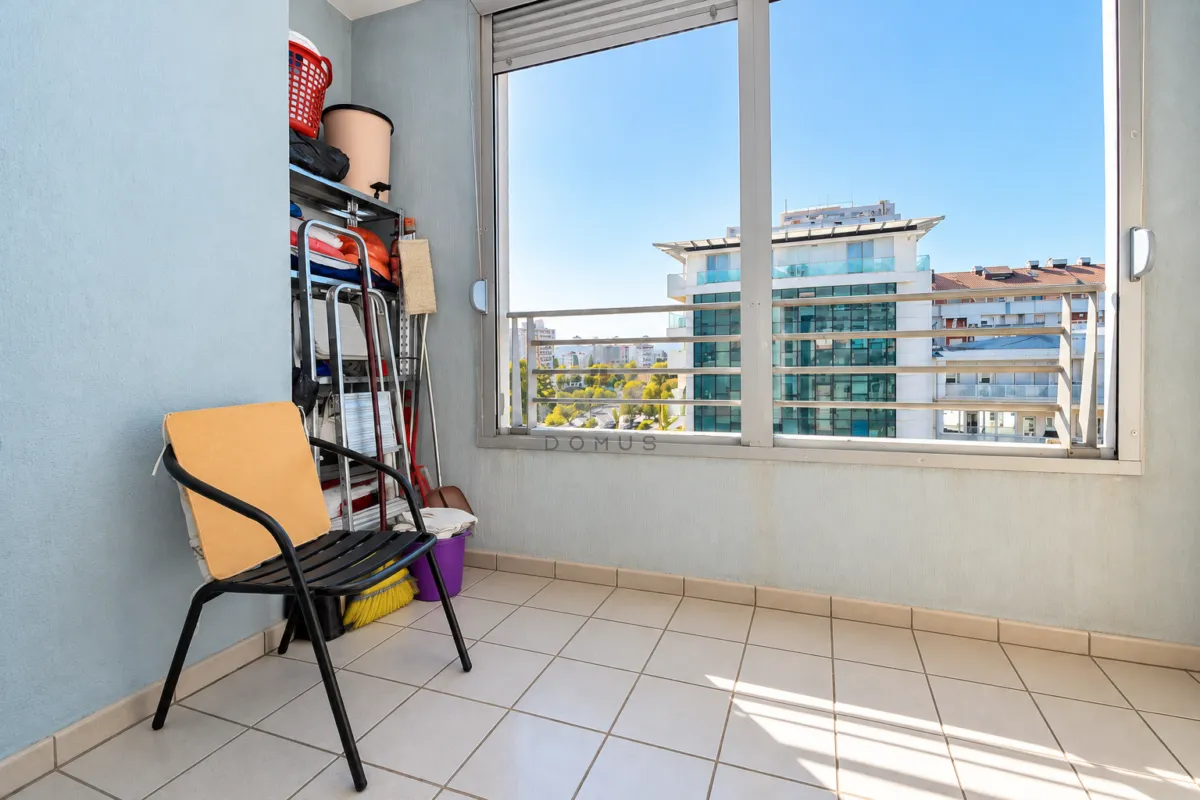 Zastakljeni balkon sa metalnom stolicom i policama za odlaganje.