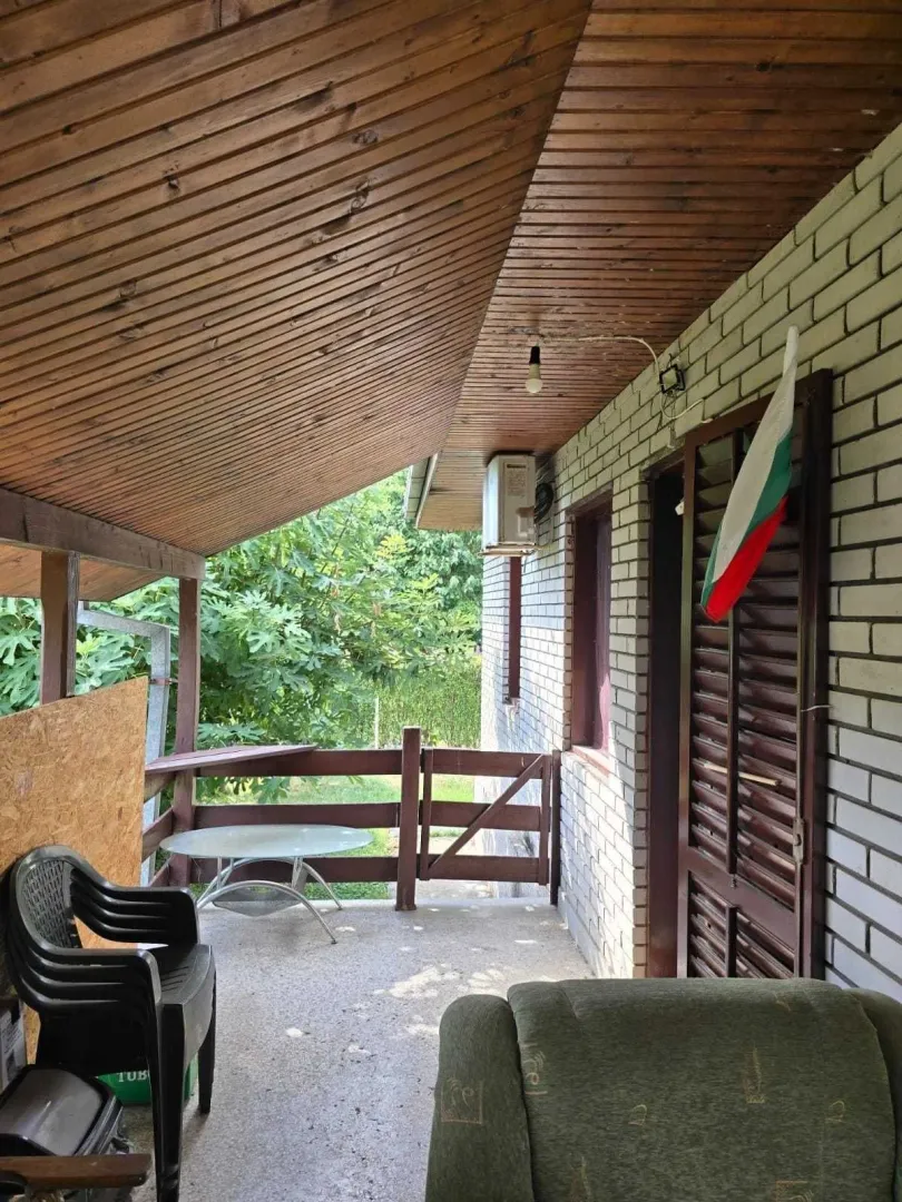 Natkrivena terasa sa drvenim plafonom i garniturom za sjedjenje.