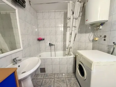 Smaller bathroom with a bathtub, washbasin, and washing machine. - image 15