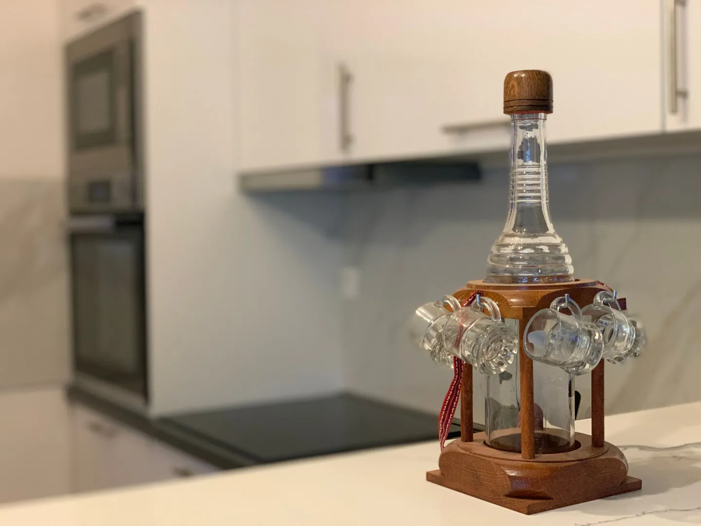 Decorative bottle with glasses on the kitchen countertop.