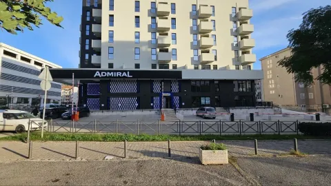 Pogled na spoljašnjost stambeno-poslovne zgrade sa ulazom i parkingom. - image 13