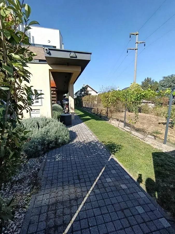 Paved walkway next to the house with a landscaped yard and lawn.